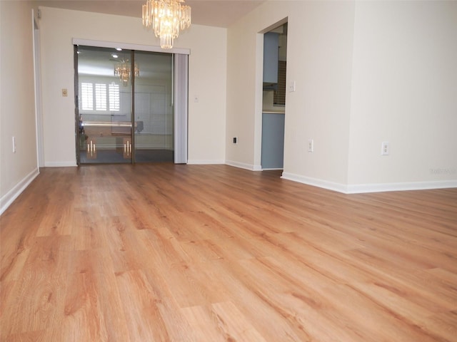 spare room with a chandelier and light hardwood / wood-style floors