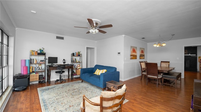 living room with a fireplace, ceiling fan with notable chandelier, dark wood-type flooring, and ornamental molding