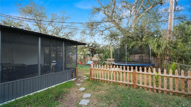 view of yard featuring a trampoline and a sunroom