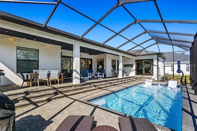 view of swimming pool featuring a patio, ceiling fan, and glass enclosure