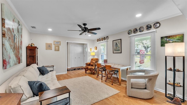 living room featuring ornamental molding, light hardwood / wood-style floors, and ceiling fan