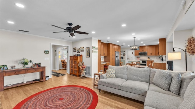 living room with crown molding, light hardwood / wood-style floors, and ceiling fan