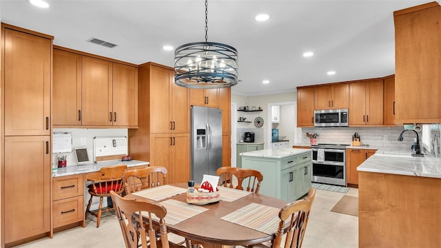 kitchen featuring sink, a center island, built in desk, hanging light fixtures, and stainless steel appliances