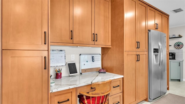 kitchen featuring light stone counters, crown molding, and stainless steel refrigerator with ice dispenser