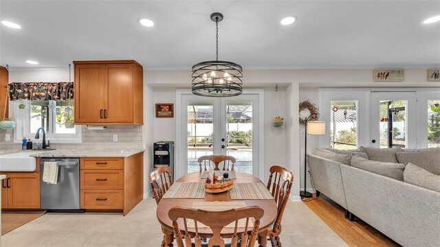 kitchen with french doors, sink, decorative light fixtures, stainless steel dishwasher, and light stone countertops