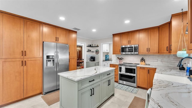 kitchen with crown molding, stainless steel appliances, tasteful backsplash, light stone countertops, and a kitchen island