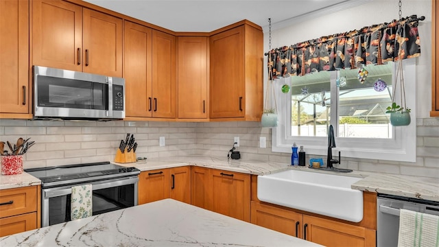 kitchen with light stone counters, appliances with stainless steel finishes, sink, and decorative backsplash