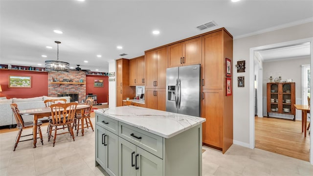 kitchen with hanging light fixtures, ornamental molding, a center island, stainless steel fridge with ice dispenser, and light stone countertops