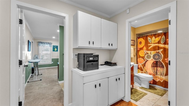 kitchen featuring crown molding, light carpet, and white cabinets