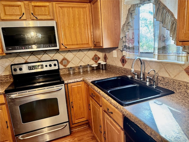 kitchen with tasteful backsplash, sink, stainless steel appliances, and light hardwood / wood-style floors