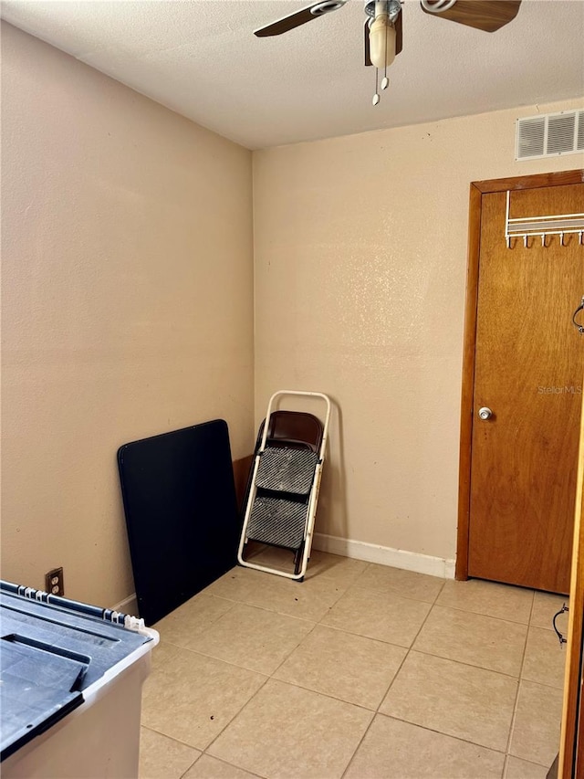 interior space featuring light tile patterned floors, baseboards, visible vents, a ceiling fan, and a textured ceiling