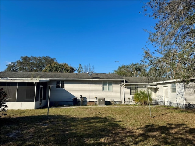 back of property with central AC unit, a lawn, and a sunroom