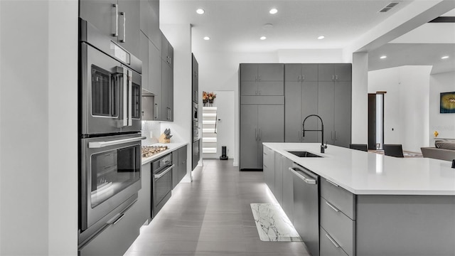 kitchen featuring stainless steel appliances, sink, and gray cabinetry