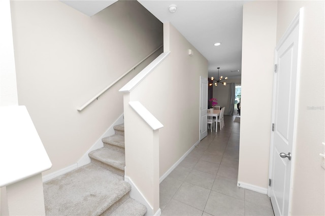 staircase featuring tile patterned flooring and an inviting chandelier