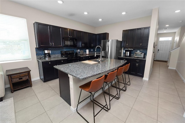 8680 Falling Blue Pl, Riverview, FL 33578 - kitchen with black appliances, a sink, decorative backsplash, light stone countertops, and a breakfast bar