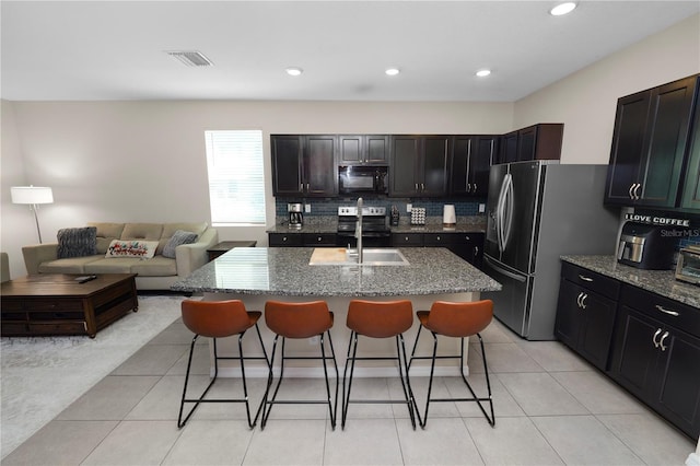 8680 Falling Blue Pl, Riverview, FL 33578 - kitchen with stainless steel appliances, a sink, a breakfast bar area, dark stone counters, and recessed lighting
