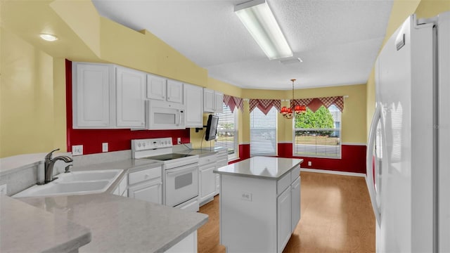 kitchen with sink, a kitchen island, pendant lighting, white appliances, and white cabinets