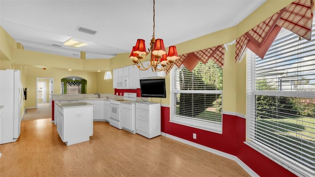 kitchen with sink, hanging light fixtures, kitchen peninsula, white appliances, and white cabinets