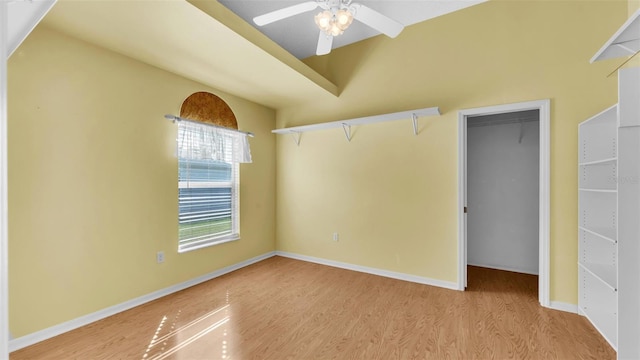 unfurnished bedroom featuring a closet, a walk in closet, ceiling fan, and light hardwood / wood-style flooring