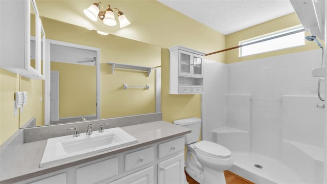 bathroom with vanity, a shower, a textured ceiling, and toilet