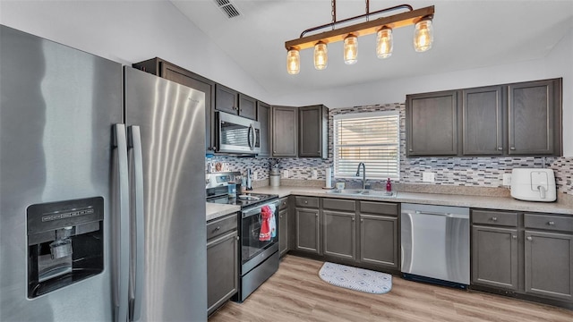 kitchen featuring pendant lighting, sink, light hardwood / wood-style flooring, and stainless steel appliances