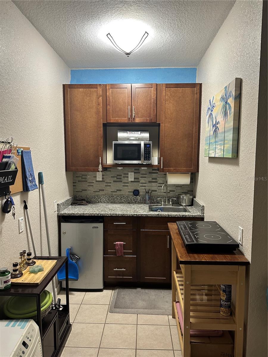 389 Nolane Ln, Polk City, FL 33868 - kitchen featuring stainless steel appliances, sink, decorative backsplash, and a textured ceiling