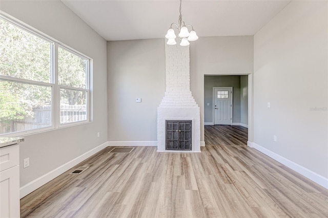 unfurnished living room featuring a notable chandelier and light hardwood / wood-style floors