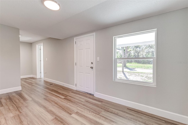 unfurnished room with a textured ceiling and light wood-type flooring