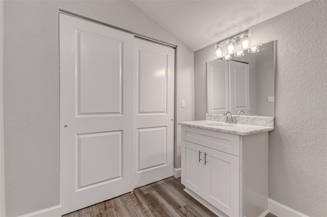 bathroom with vanity, vaulted ceiling, and wood-type flooring