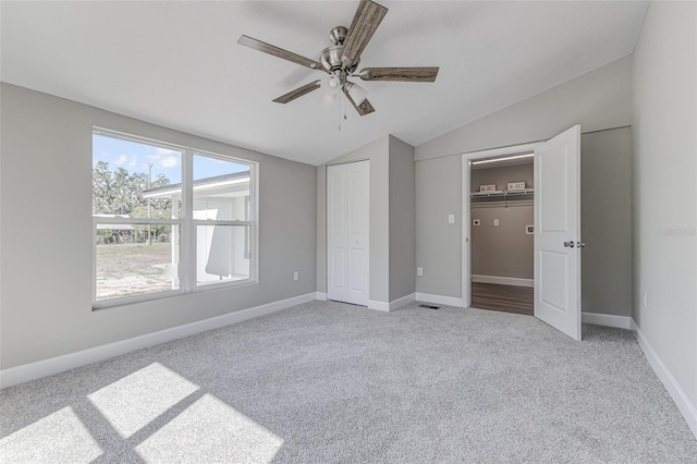 unfurnished bedroom featuring lofted ceiling, light colored carpet, a closet, and ceiling fan