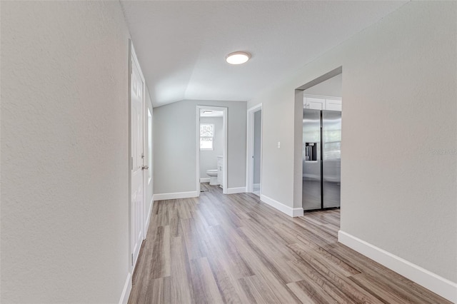 empty room with vaulted ceiling and light hardwood / wood-style floors