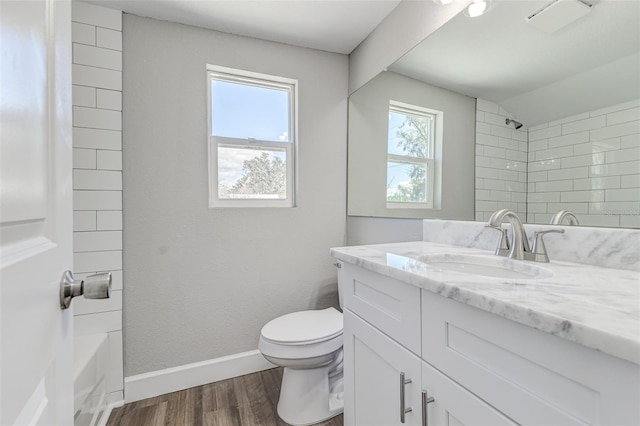 full bathroom with vanity, hardwood / wood-style flooring, tiled shower / bath combo, and toilet