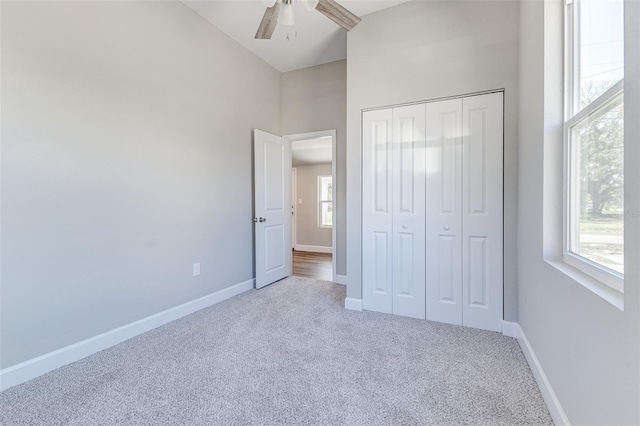 unfurnished bedroom with a high ceiling, carpet floors, ceiling fan, and a closet