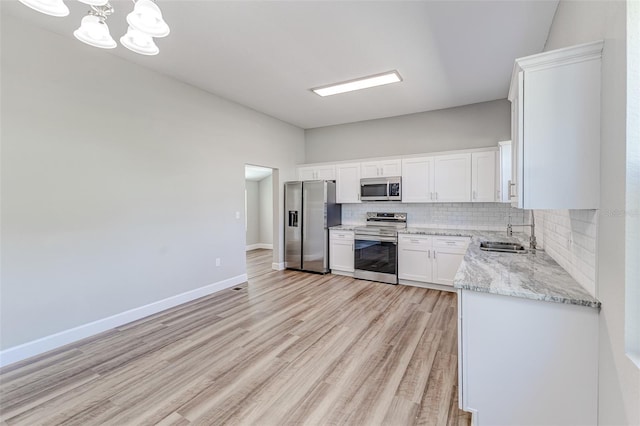 kitchen with white cabinetry, sink, backsplash, stainless steel appliances, and light hardwood / wood-style flooring