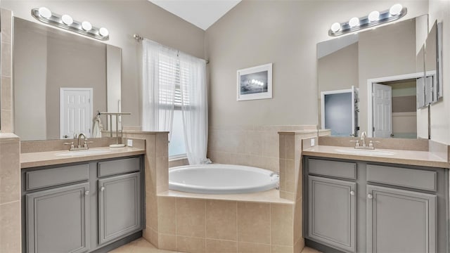 bathroom featuring a sink, two vanities, and a bath