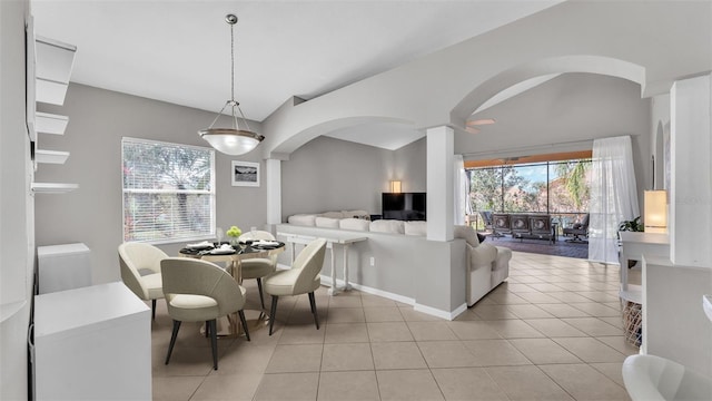 dining space with light tile patterned floors, arched walkways, ornate columns, and vaulted ceiling