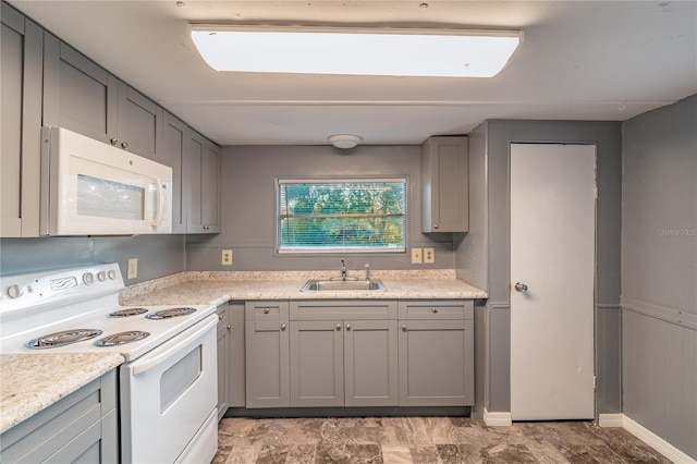 kitchen with light countertops, white appliances, a sink, and gray cabinetry