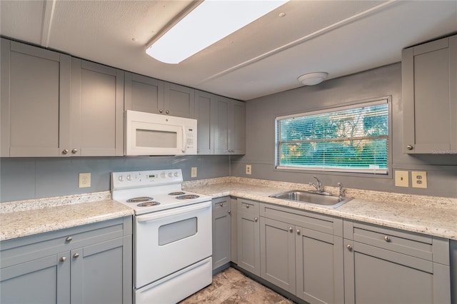 kitchen featuring gray cabinets, white appliances, a sink, and light stone countertops