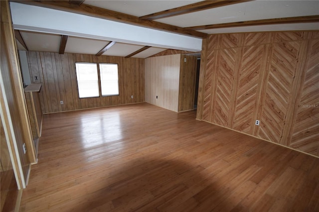 interior space featuring wooden walls, light wood-style flooring, and lofted ceiling with beams