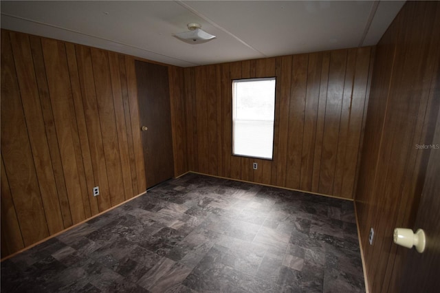 unfurnished room featuring wooden walls and dark floors