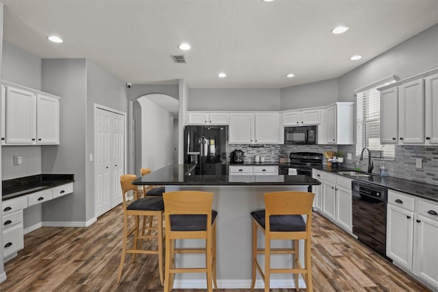 kitchen featuring white cabinets, a center island, sink, and black appliances