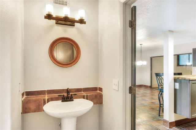 bathroom featuring an inviting chandelier, tile patterned floors, and sink