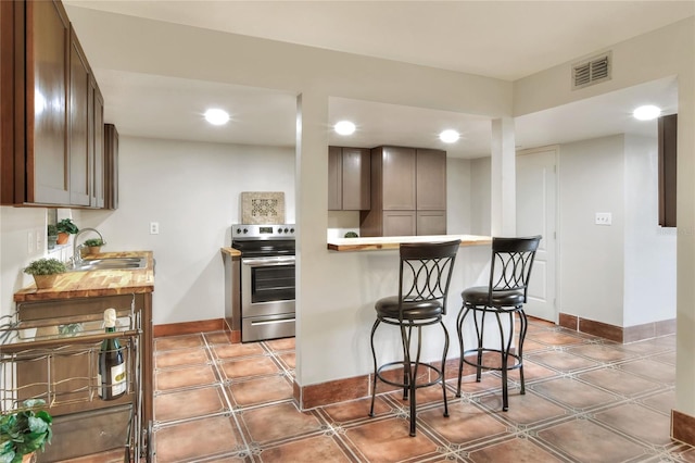 kitchen with a breakfast bar, sink, kitchen peninsula, and stainless steel range with electric stovetop