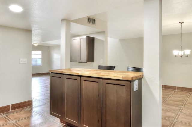 kitchen featuring butcher block counters, a notable chandelier, pendant lighting, and dark brown cabinetry