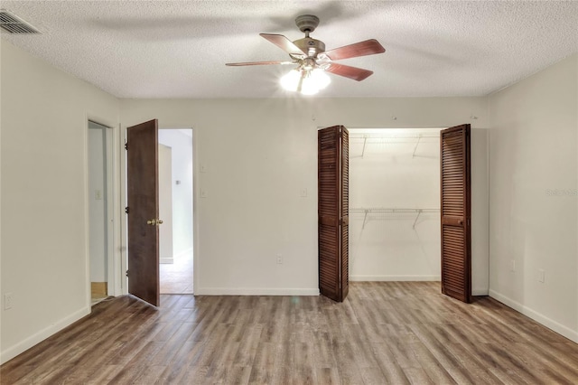 unfurnished bedroom with a closet, ceiling fan, a textured ceiling, and light hardwood / wood-style flooring