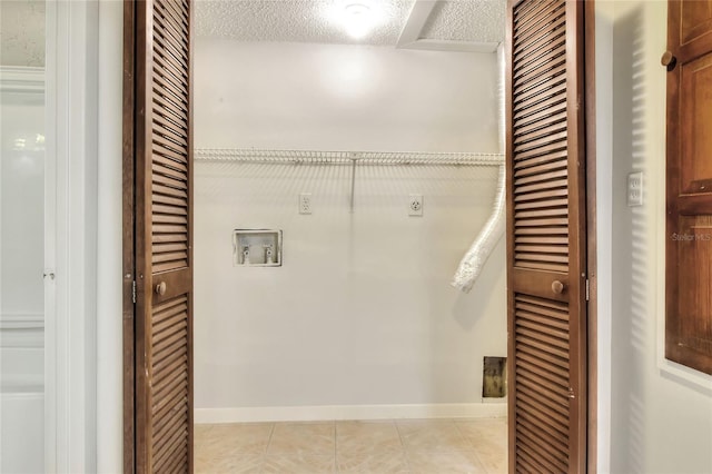 laundry area with washer hookup, hookup for an electric dryer, a textured ceiling, and light tile patterned floors