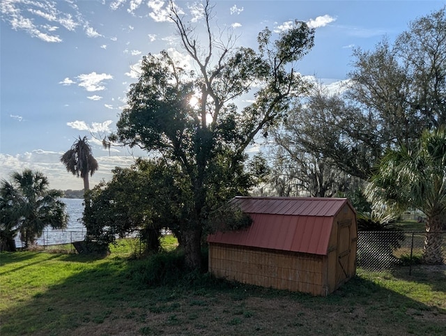 view of outbuilding with a lawn and a water view