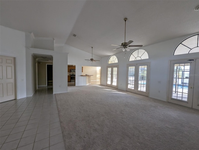 unfurnished living room featuring ceiling fan, light carpet, high vaulted ceiling, and french doors