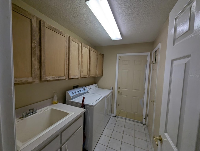 clothes washing area featuring sink, washing machine and dryer, cabinets, a textured ceiling, and light tile patterned flooring