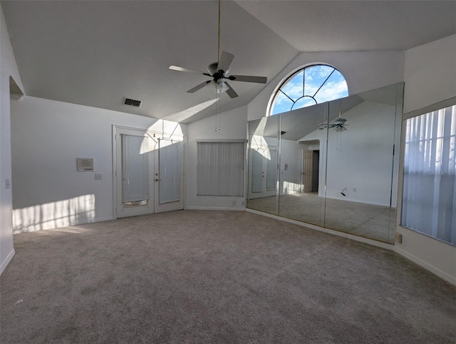 unfurnished living room with a wealth of natural light, high vaulted ceiling, ceiling fan, and carpet flooring